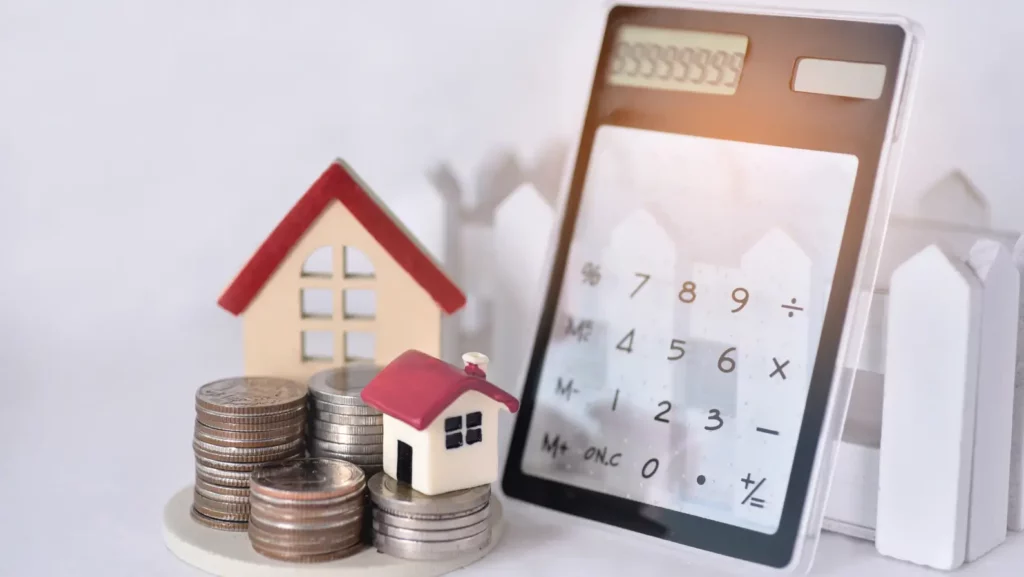 Stacking coins with the two red roof house and the calculator lean against the sunrise for calculate the home payment interest of house loan monthly installment or an equated monthly installment