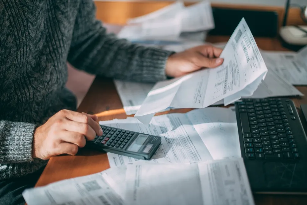 Person calculating expenses and bills to budget for the best ROI home improvements in Houston.