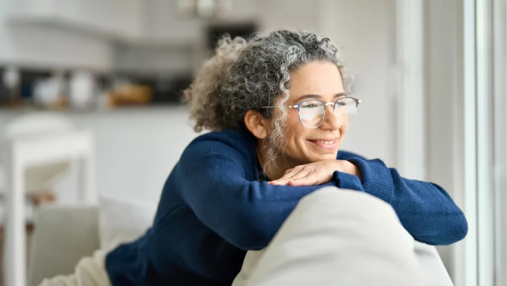 Woman smiling while relaxing at home, representing the comfort and lifestyle options in 55 Communities In Houston.