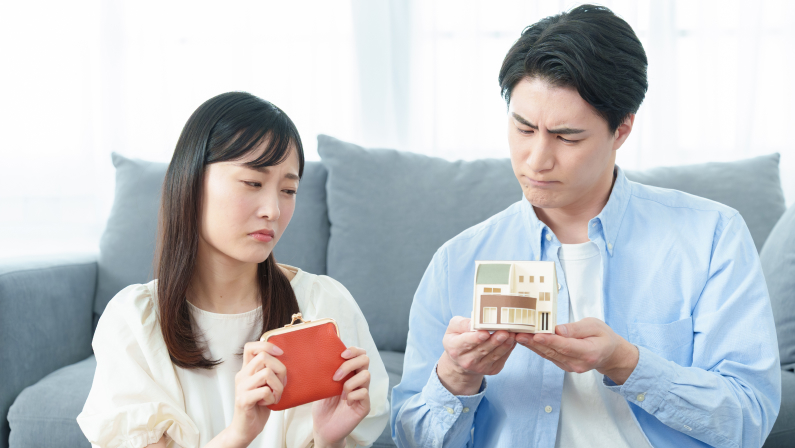 young asian couple with worried expression wondering whether to buy a real estate. holding a wallet and a miniature house.