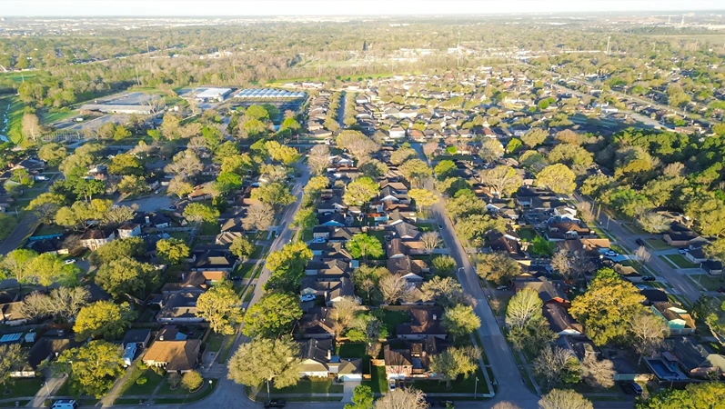 Greater Inwood residential neighborhood and grass lined drainage channel in northwest part of Houston, Texas, aerial view suburban residential houses and townhomes surrounding by lush green trees. USA