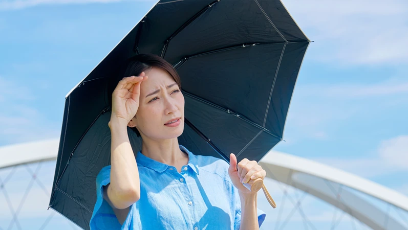 Asian middle aged woman holding a parasol outdoors